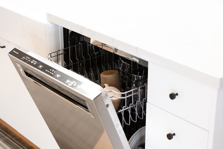 Open dishwasher in white kitchen.