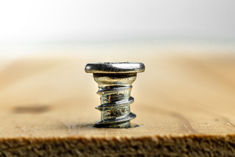 Closeup of screw being screwed into a wooden plank - macro shoot - white background