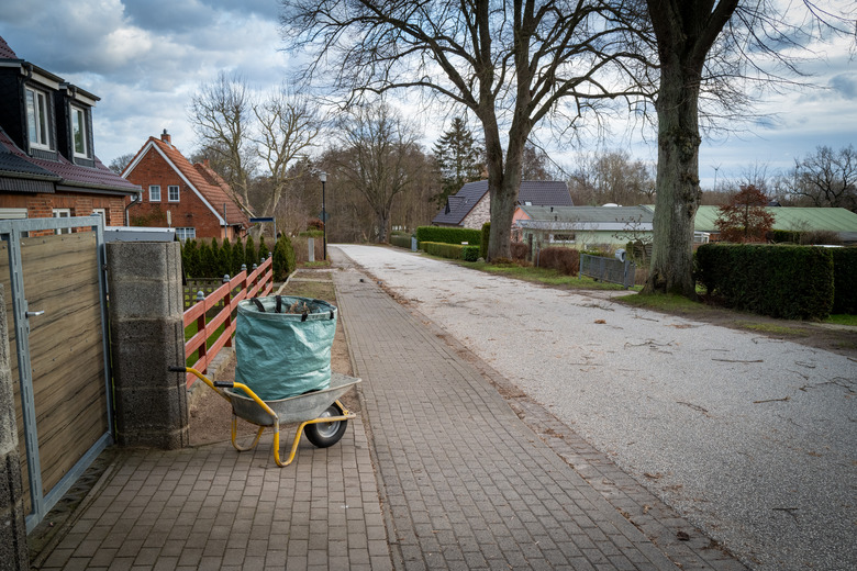 on the sidewalk is a wheelbarrow with a garbage bag on it