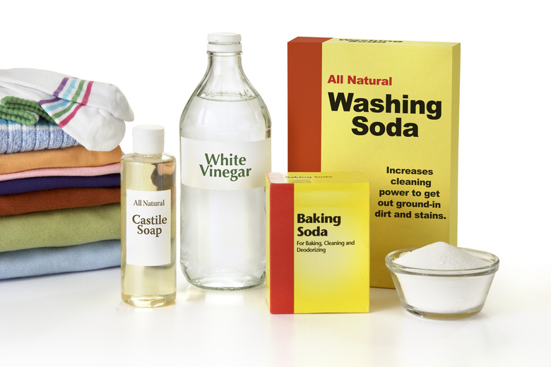 Washing soda, Castile soap, white vinegar, baking soda beside a stack of clean, folded laundry