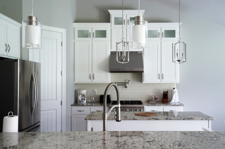 Interior design and kitchen architecture decorated with white wooden furniture, marbled materials and built in appliances