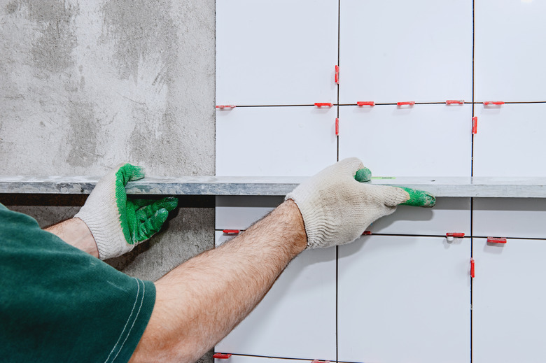 Ceramic tiles. The master lays ceramic tiles on the wall and draws them out using a special level.