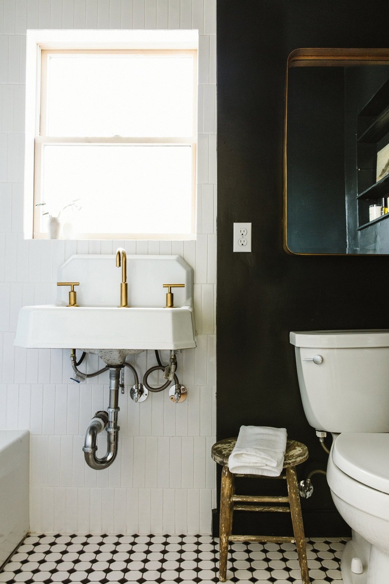 sink with a gold faucet and black wall in a bathroom