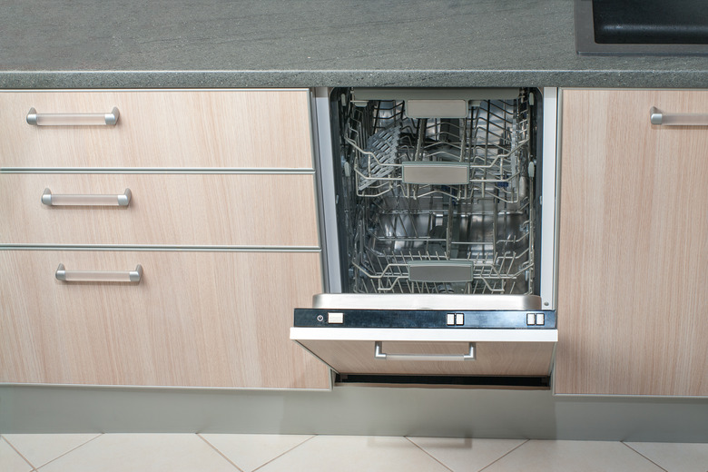 Open empty dishwasher in kitchen. Modern smart electronic housekeeping technology