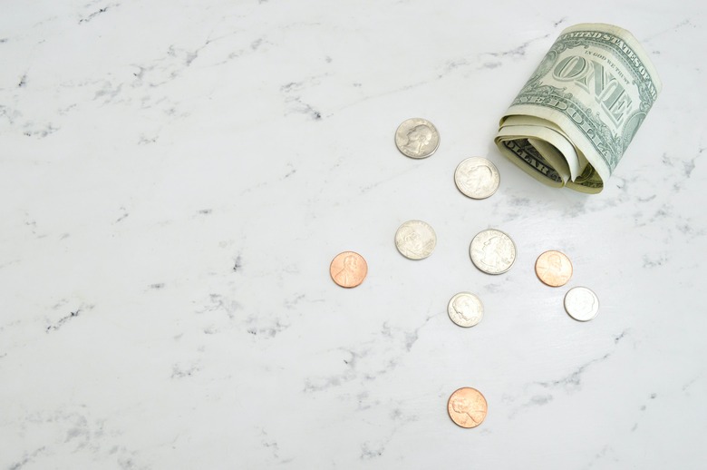 coins and dollar bills on a white marble surface