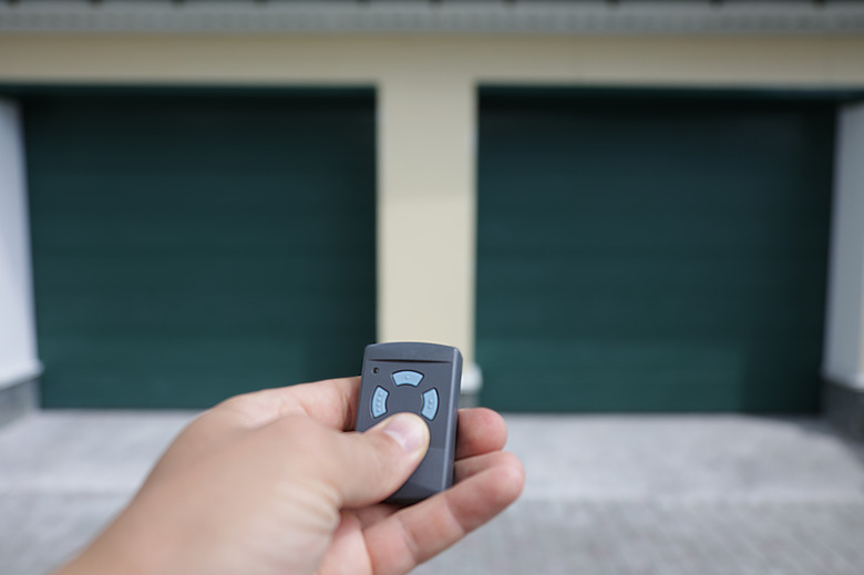 Man holds in his hand a remote control that opens the garage door