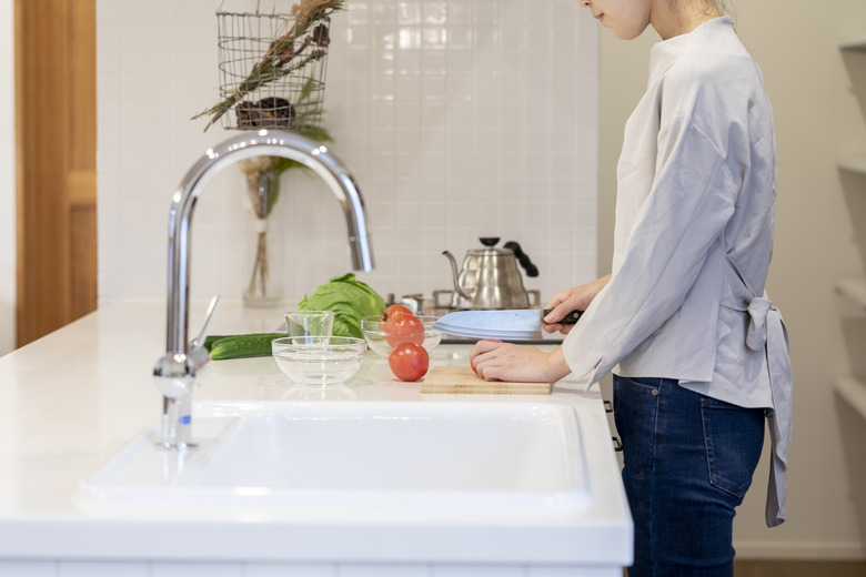 Hands of a young woman cutting vegetables in the kitchen