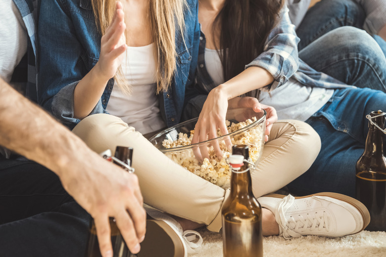 Sitting on floor drinking beer and eating popcorn.