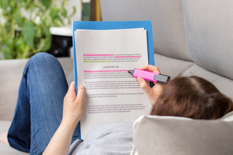 Woman studying via highlighting in a notebook.