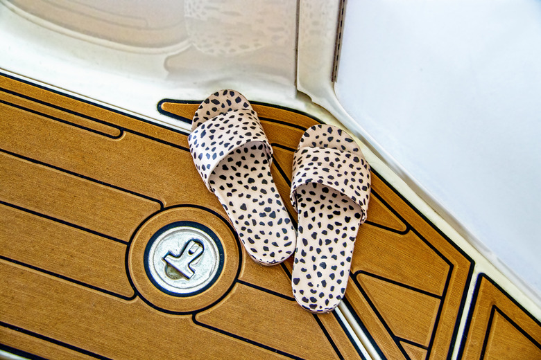 Leopard print slides sitting on synthetic teak boat decking.