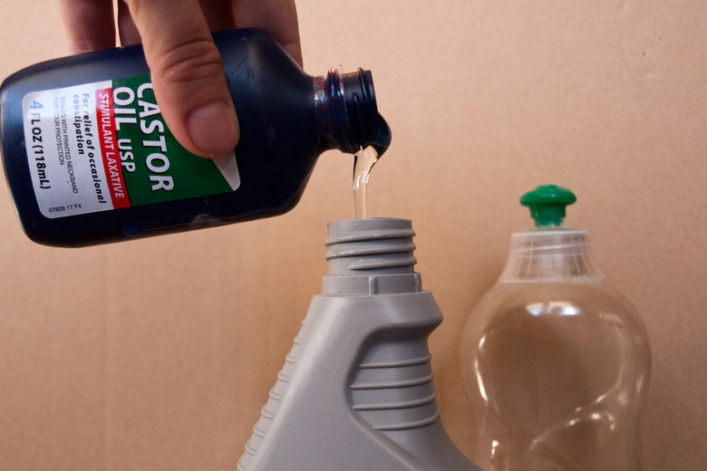 Person pouring caster oil into a garden sprayer