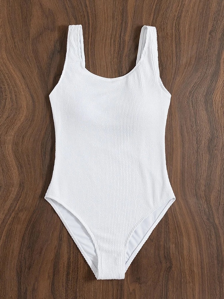 A white one-piece bathing suit on a wood table