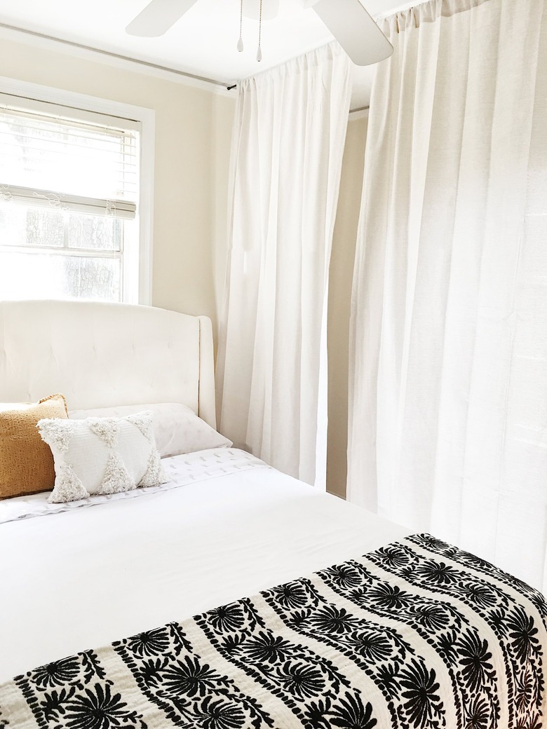 a bed with curtains hanging from the ceiling around it to create a canopy