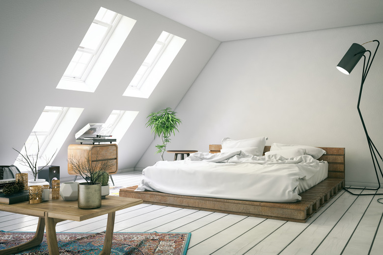 White loft bedroom with slanted wall and dormer windows..