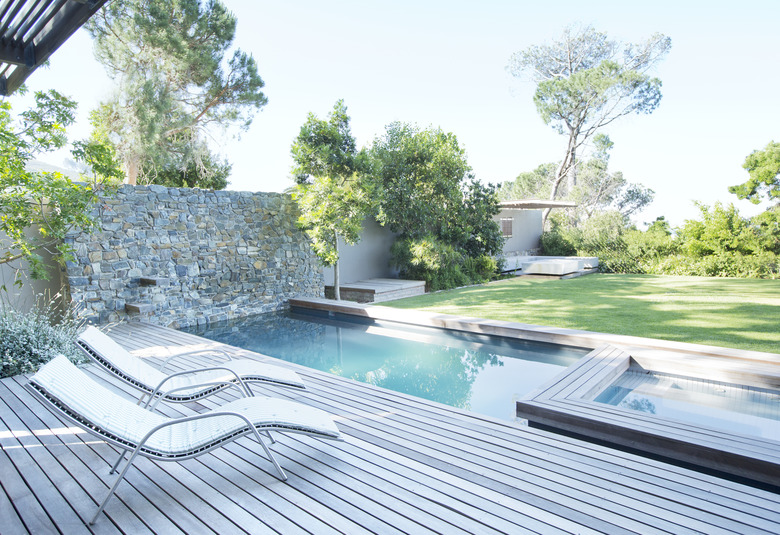 Lawn chairs and swimming pool in backyard.