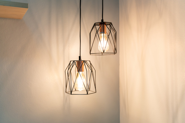 Illuminated Light Bulb Hanging On Wall At Home