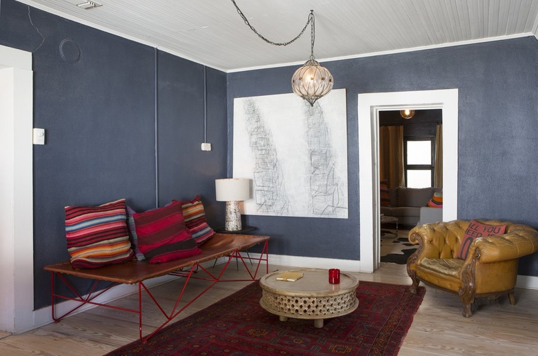 Boho living room with gray walls, leather chair, colorful bench pillows