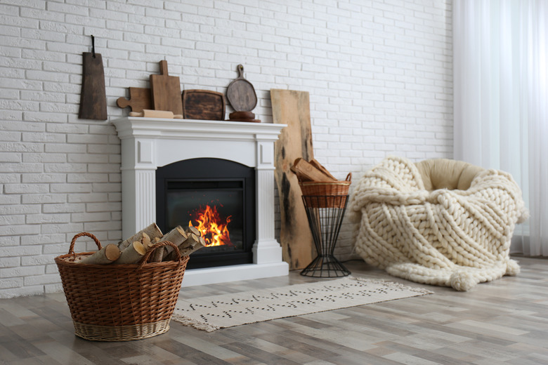 Wicker baskets with firewood and white fireplace in cozy living room