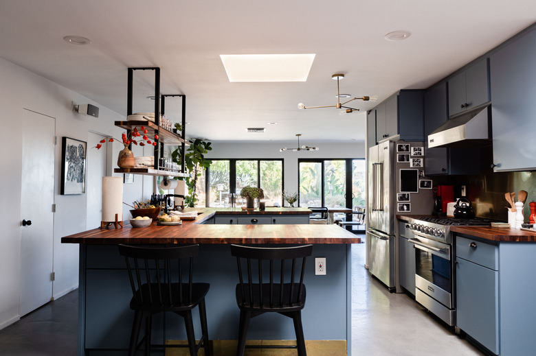 kitchen with blue cabinetry, wood countertops, hanging shelves