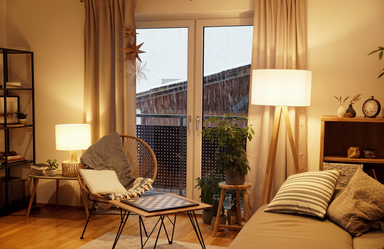 View of a warm, light, cozy living room in winter with a snowstorm outside.