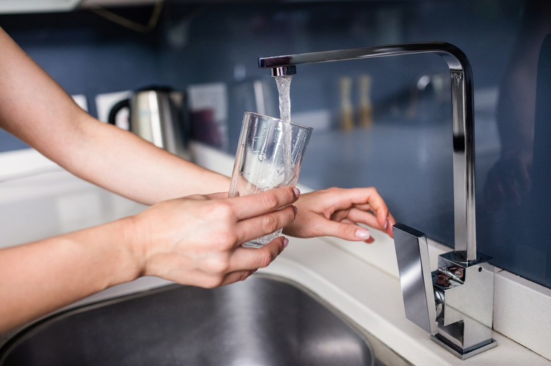 Woman filling water in glass at kitchen sink