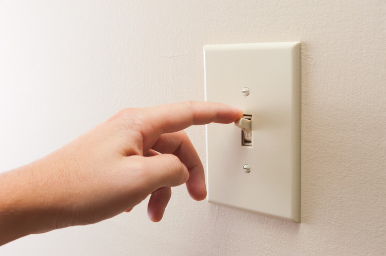 Hand turning wall light switch off