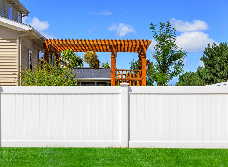 Partial view of solid white vinyl fence between yards