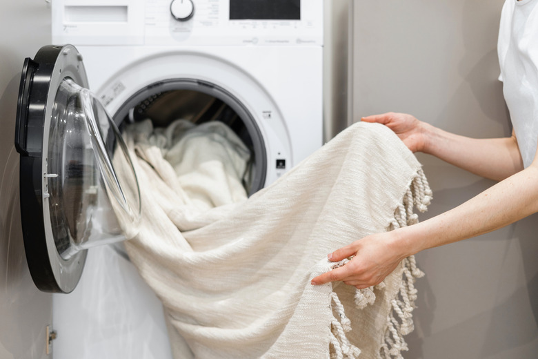 Unloading laundry from white washing machine.