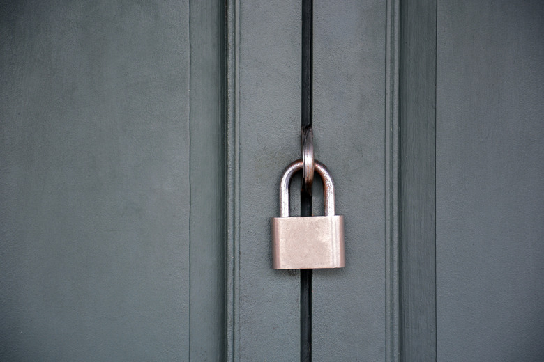 Old house door padlock is locked with a rusty key.