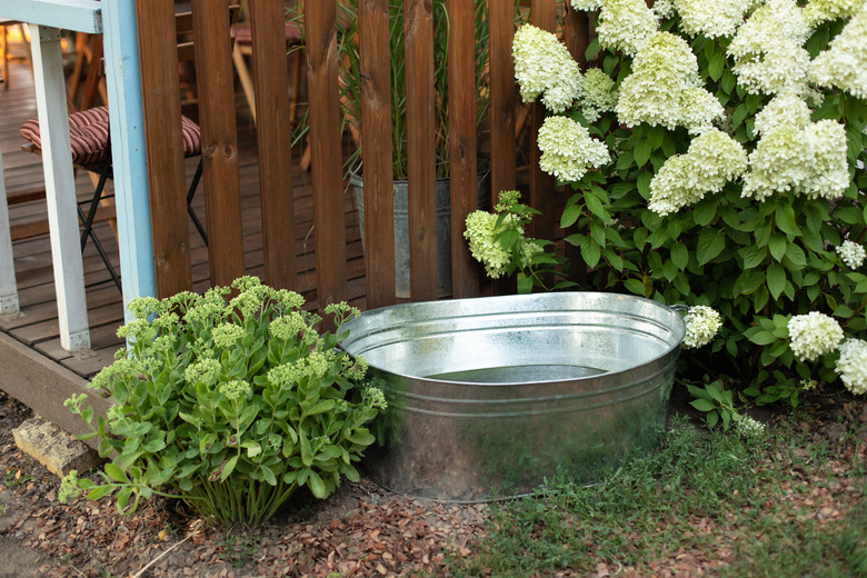 Galvanized tub in garden against wooden wall.