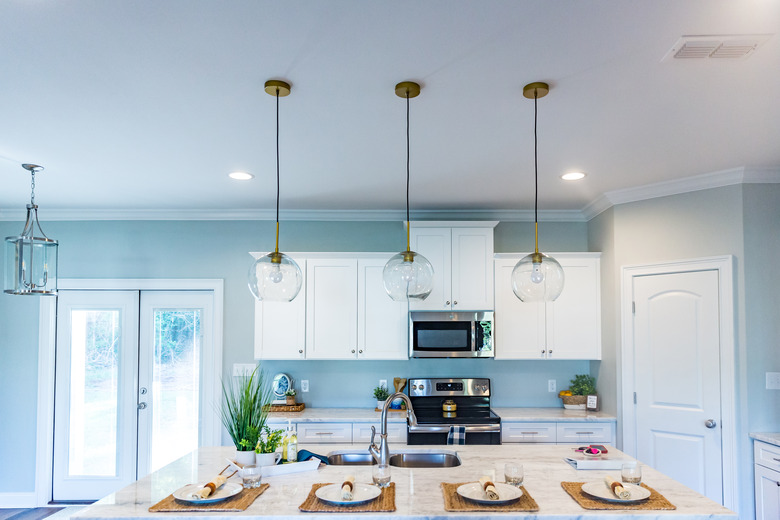 Open floor plan kitchen in a new construction empty house that has just been completed with white cabinets, pendant lighting, a bar area and hardwood floors