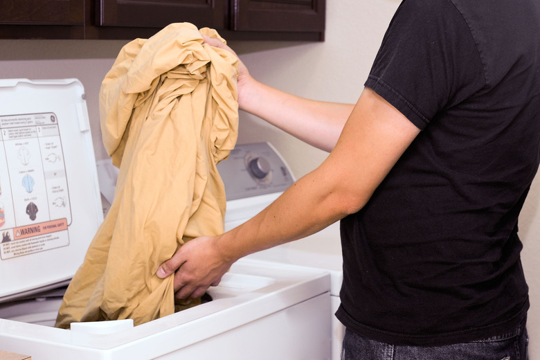 A woman shaking out sheets before she places them in the dryer