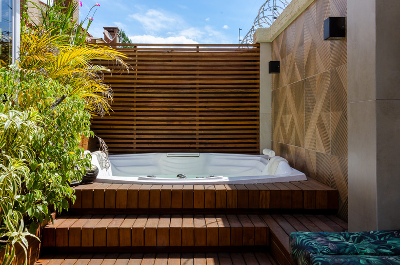 Garden wooden deck with a hot tub in sunlight.