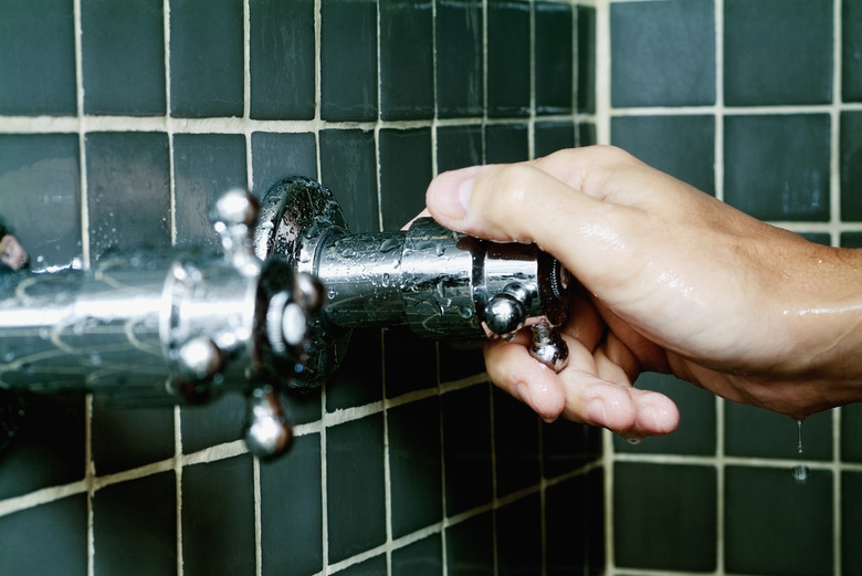 Close-up of a person's hand turning a shower knob