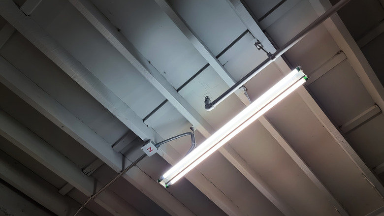 unfinished ceiling showing beam structure, electrical system, piping system and fluorescent lighting. industrial or loft style of interior decoration. bare ceiling for construction concept.