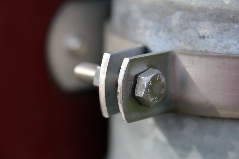 Grey metallic rainwater pipe attached to a building with a metal ring.