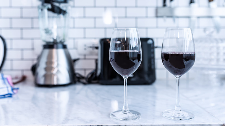 Red wine  in the glass In the modern kitchen . Classic white wall background .