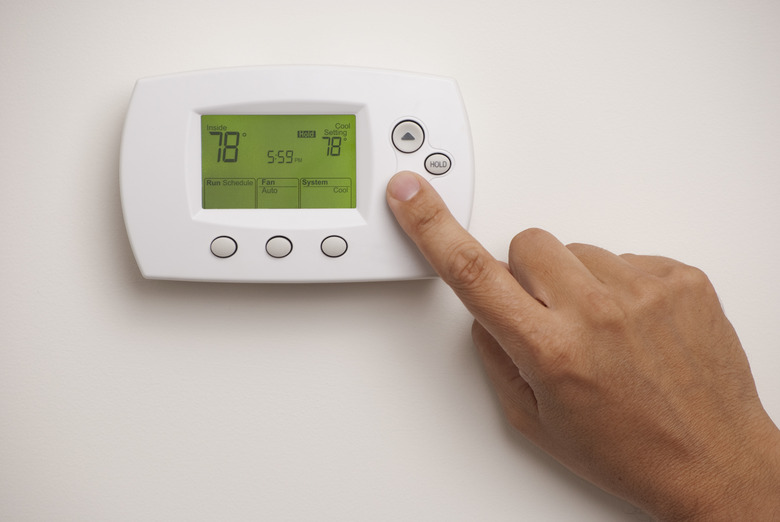 Male hand on digital thermostat set at 78 degrees