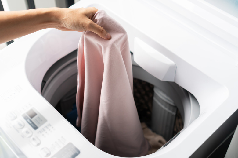 Putting  clothes in washing machine.