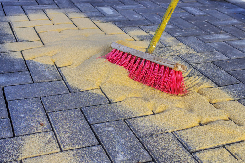 Sweeping in joint sand on a construction site.