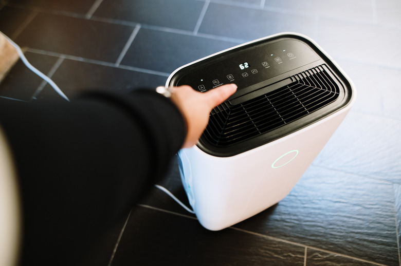 Hand pressing a dehumidifier button