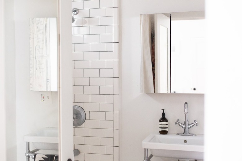 Minimalist white walled bathroom, with a white tiled shower wall.