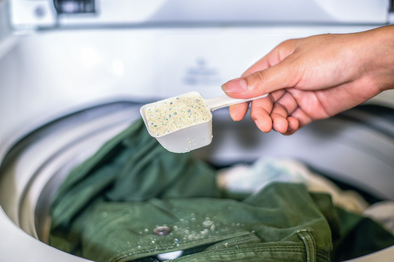 Adding powdered detergent to washing machine.