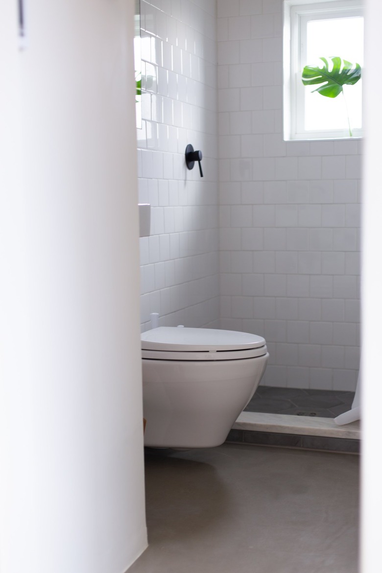 Bathroom with white toilet and white tile and window in shower