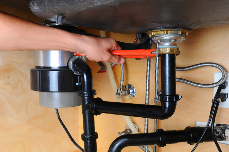 Plumber Using Wrench Under Kitchen Sink