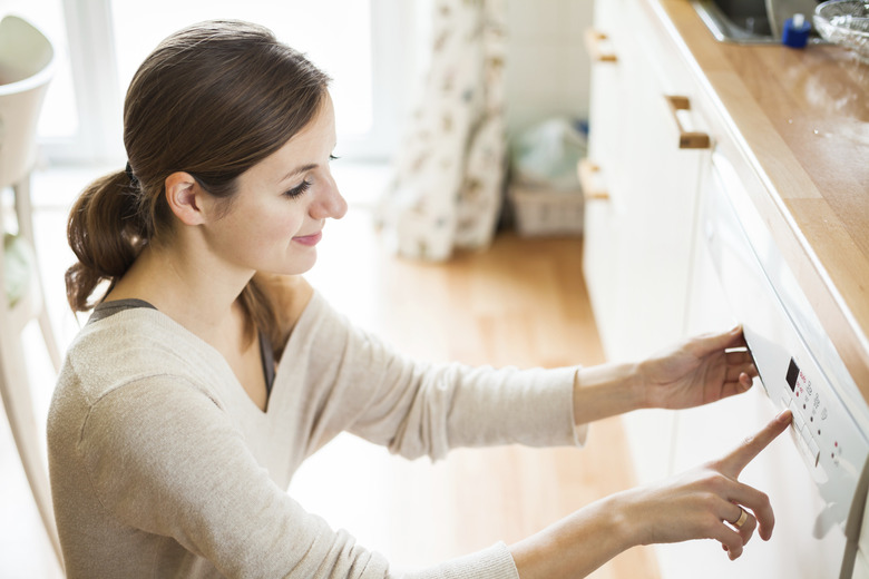 Young woman putting dishes in the dishwasher