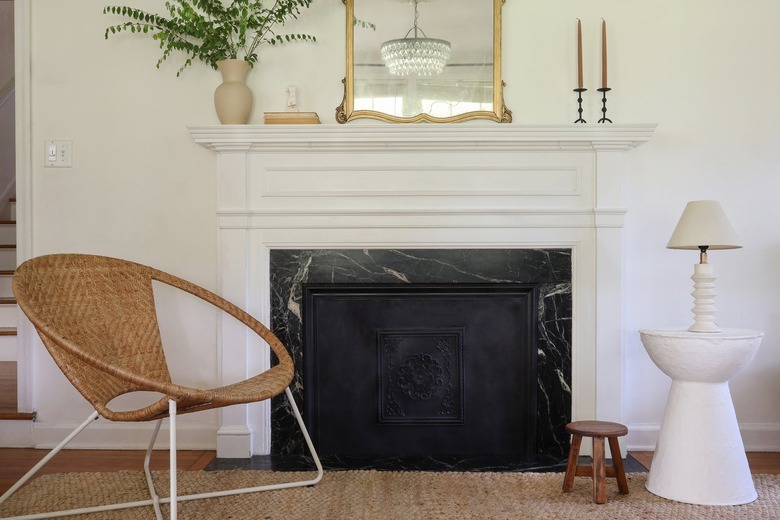 A black Victorian-style fireplace cover accented with traditional and modernist accent pieces