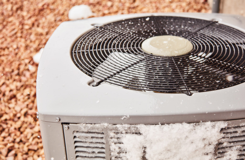 Residential air conditioning unit covered in snow during a summer snow storm in Colorado