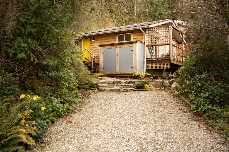 Driveway leading up to a rustic wooden cabin in the woods