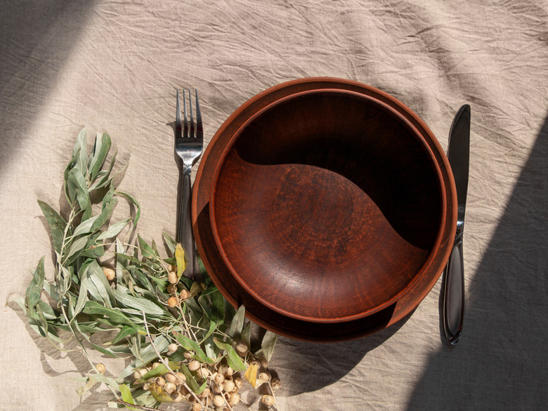 Empty craft handmade clay plate with fork and knife on tablecloth.